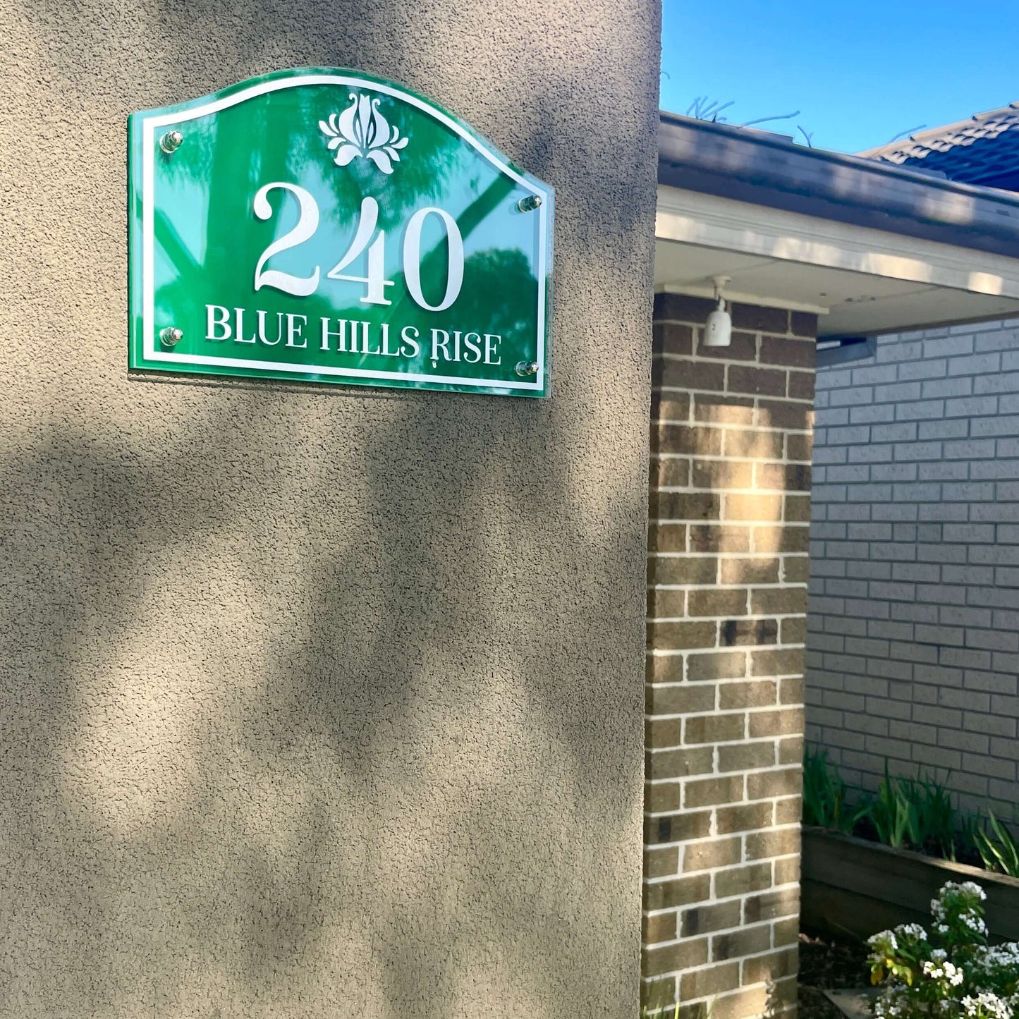 House number sign 240 Blue Hills Rise installed on a wall, showcasing a green, decorative plaque for homes.
