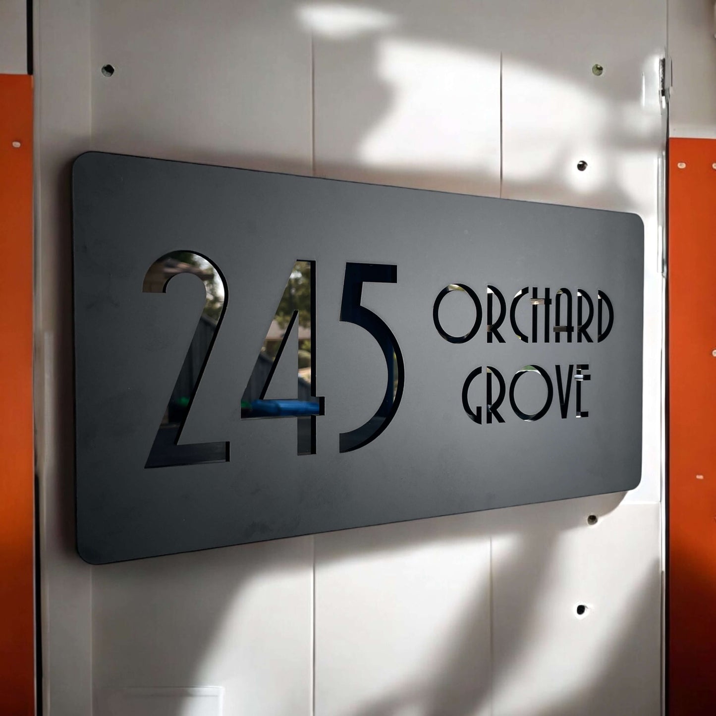 Stylish SW2 house number sign reading '245 Orchard Grove' in modern design on a door.