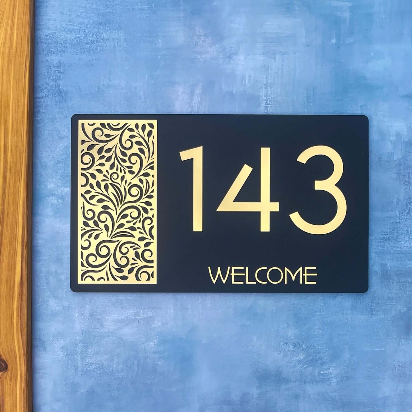 "Modern black and gold house number sign with decorative pattern and '143 Welcome' text, suitable for SW2 style home."