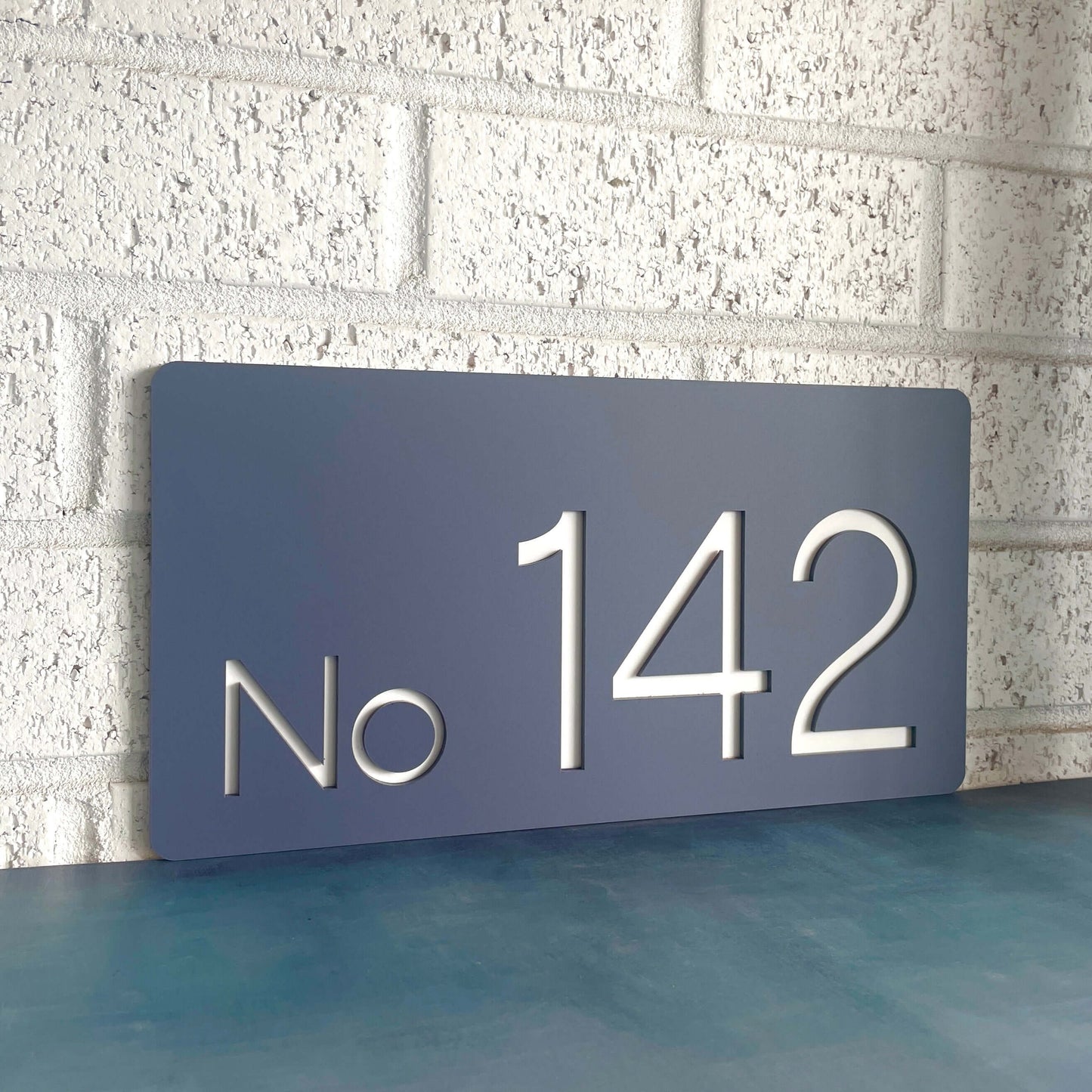 Nouveau 3 SW2 house number sign "No 142" on a white brick wall, Australian made, DIY installation, weather-resistant.