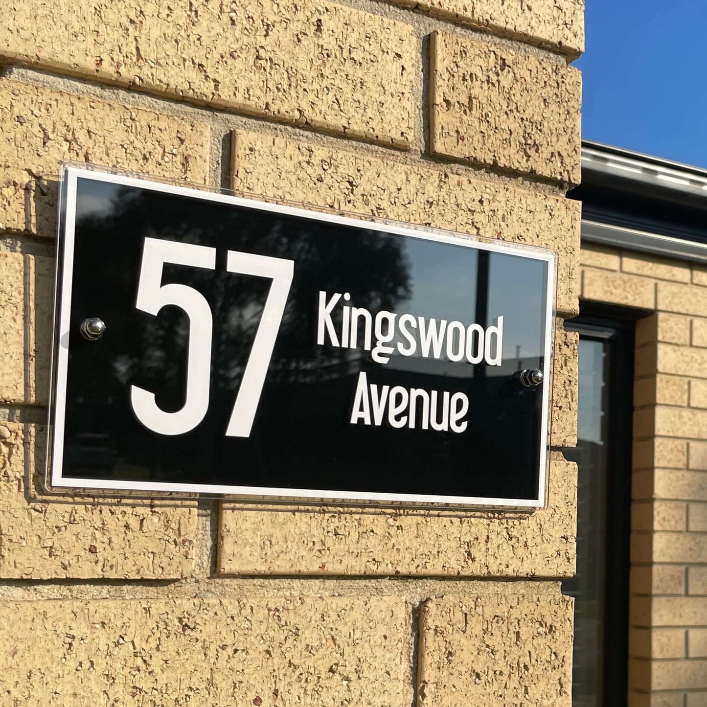 House number sign with '57 Kingswood Avenue' mounted on brick wall, SW2