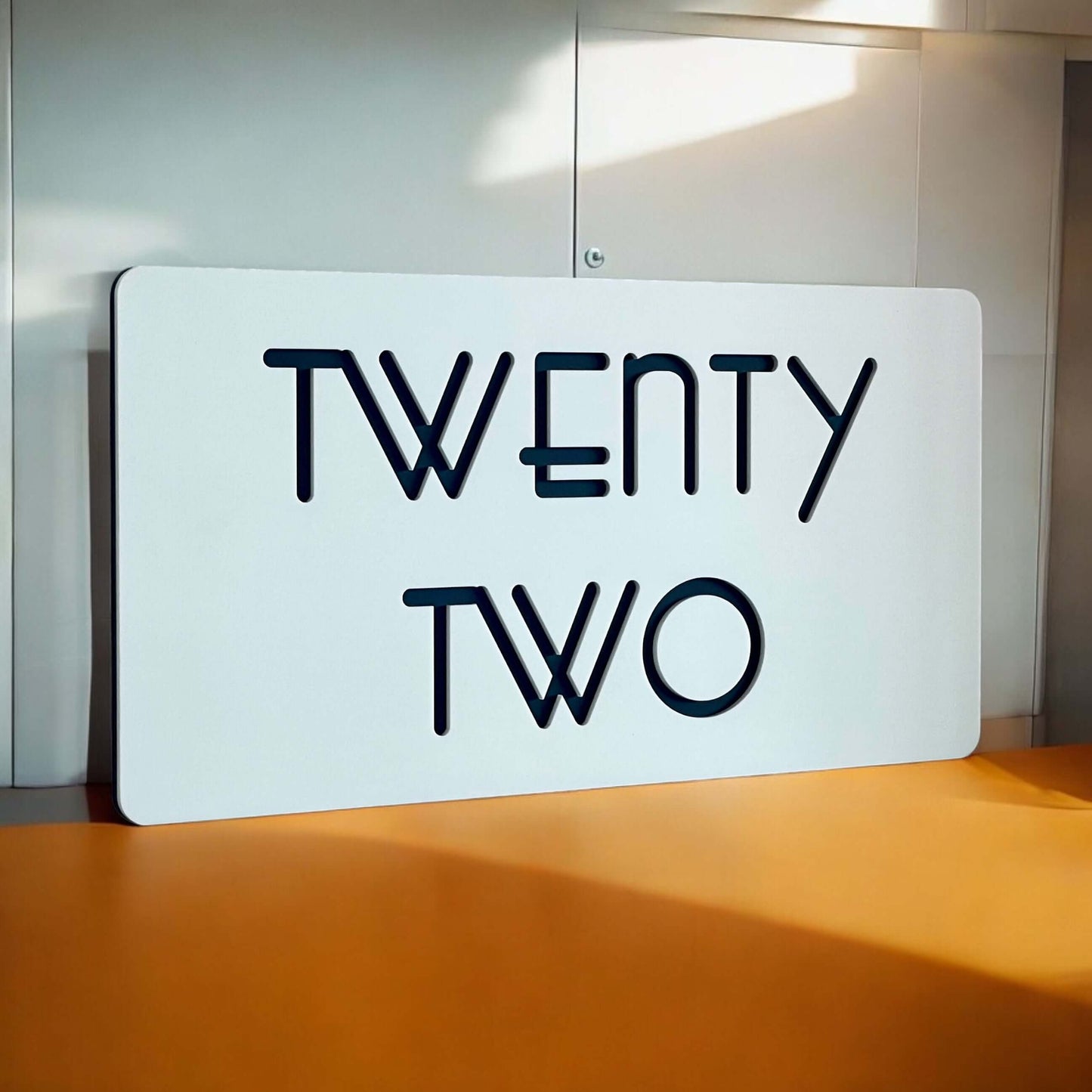 Stylish 'TWENTY TWO' house number sign with modern design on a smooth surface, suitable for DIY installation. Australian made.