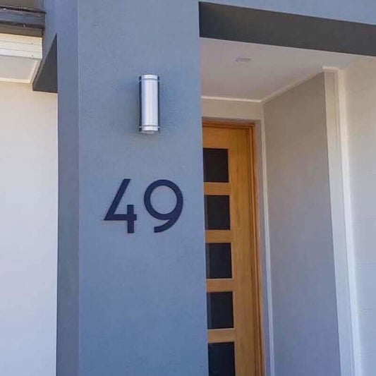 House facade with large black number 49, Australian made SW2 house number sign, beside a modern wooden door.
