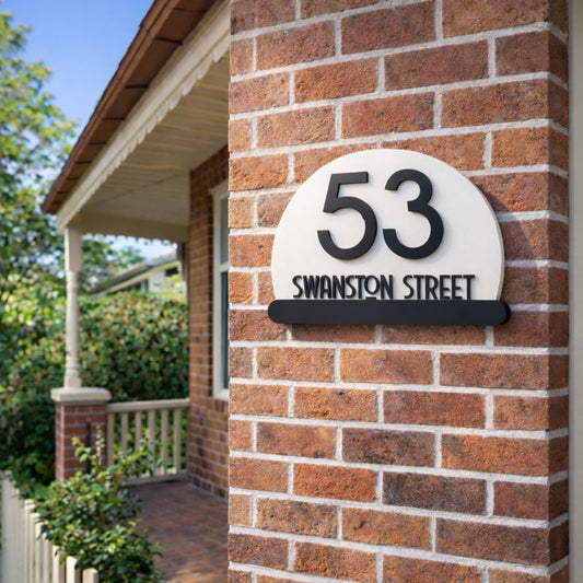 Half Moon house number sign in gloss white acrylic with raised black numerals  street name mounted on a red brick wall using invisible rear fixings
