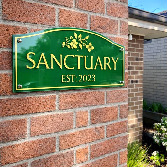 Heritage traditional acrylic house name sign in green with gold vinyl lettering "Sanctuary Est. 2023" mounted on a red brick wall at a classic Australian home