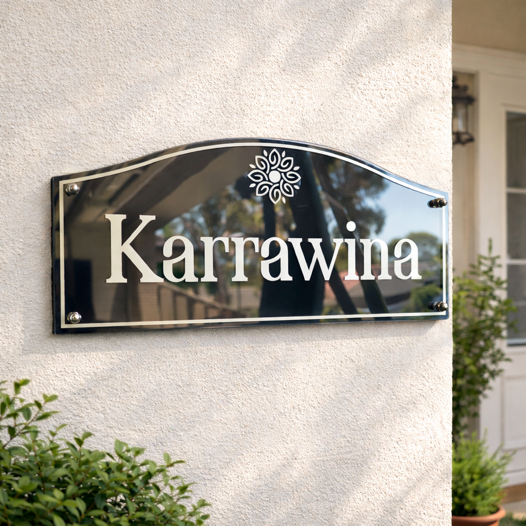 Heritage style house sign with 'Karrawina' on a textured wall with plants around
