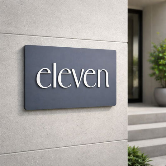 Legacy L3 3D rectangular house sign in Stormy Grey acrylic with raised lettering spelling "eleven" mounted on a light grey rendered wall
