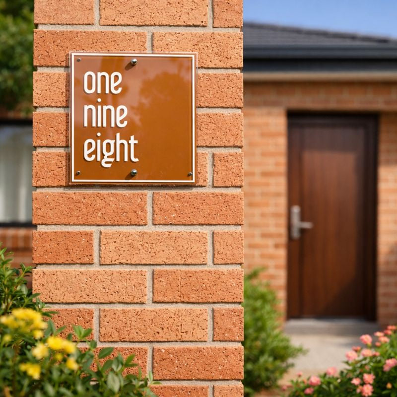 Metro 5 square house number sign in warm copper with white vinyl house number "198" mounted on a red brick pillar