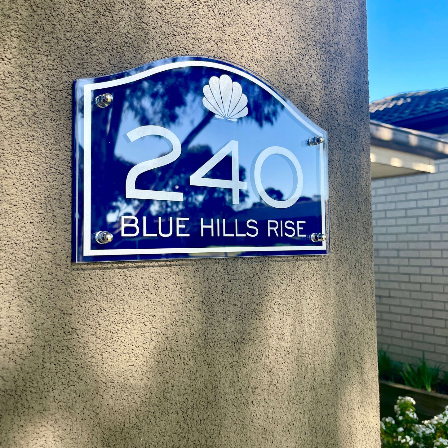 Australian made SW2 house number sign in blue, displaying '240 Blue Hills Rise' on a wall with stylish heritage design.