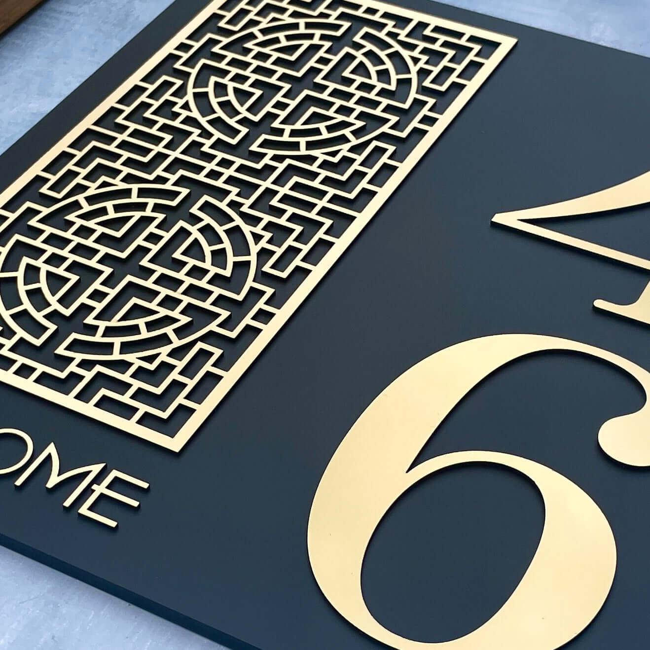 Close-up of SW2 house number sign with intricate patterned design and large gold numbers, suitable for DIY installation.