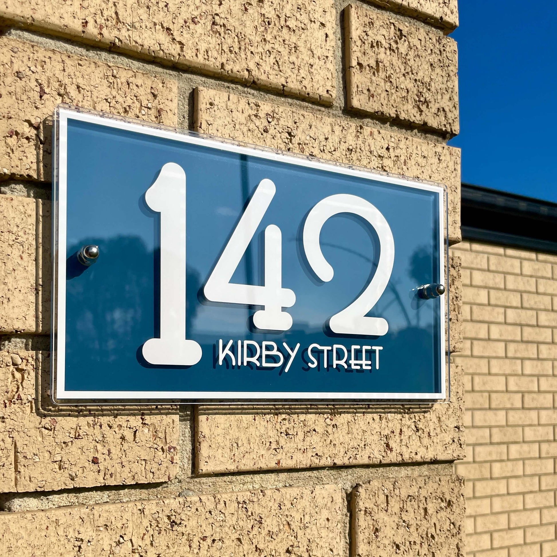 Modern Australian-made SW2 house number sign "142 Kirby Street" on brick wall, easy DIY installation with peel-and-stick tape.
