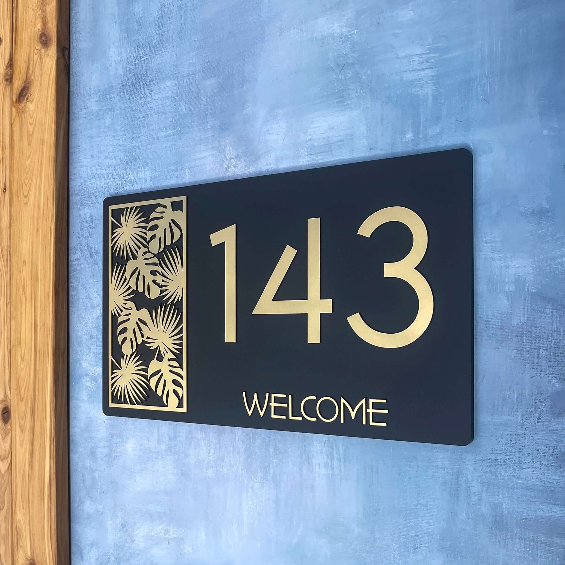 Outdoor house number sign with '143' and 'WELCOME', featuring decorative leaf design. Australian made Lustre L3 SW2.