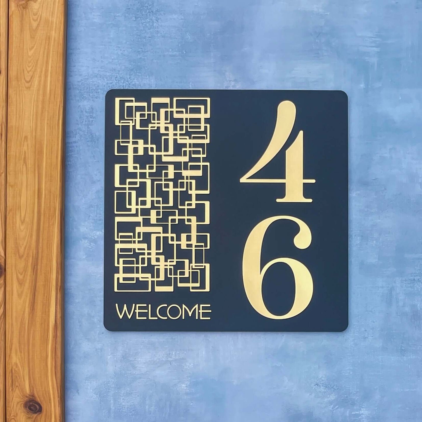 "SW2 house number sign with geometric pattern, displaying numbers 46 and 'Welcome' text, mounted on a blue wall."