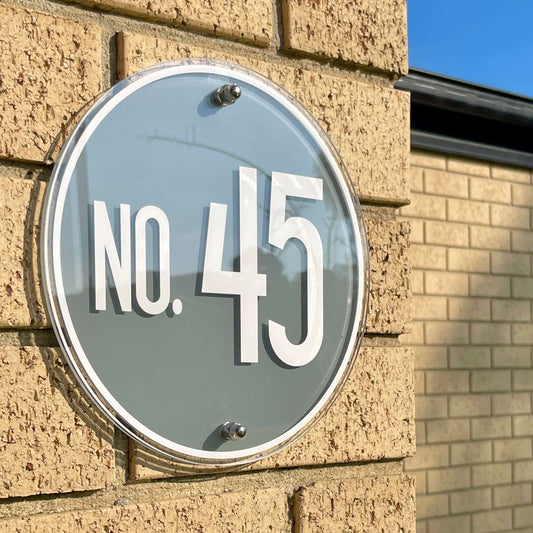 Modern SW2 house number sign mounted on brick wall, displaying 'No. 45', showcasing its sleek design and simple installation method.