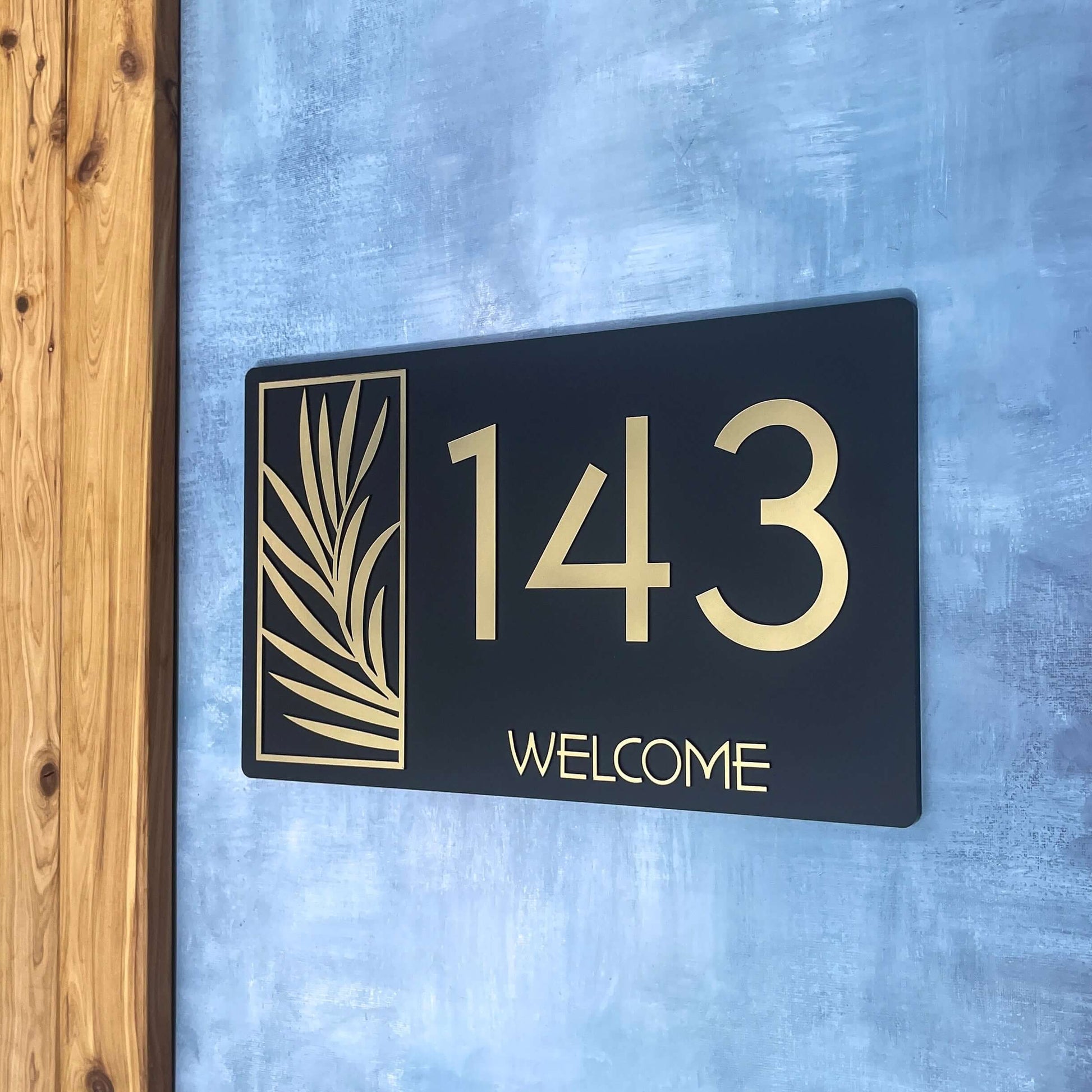 Stylish house number sign 143 on blue wall, featuring elegant gold accents and decorative design, best for modern homes.