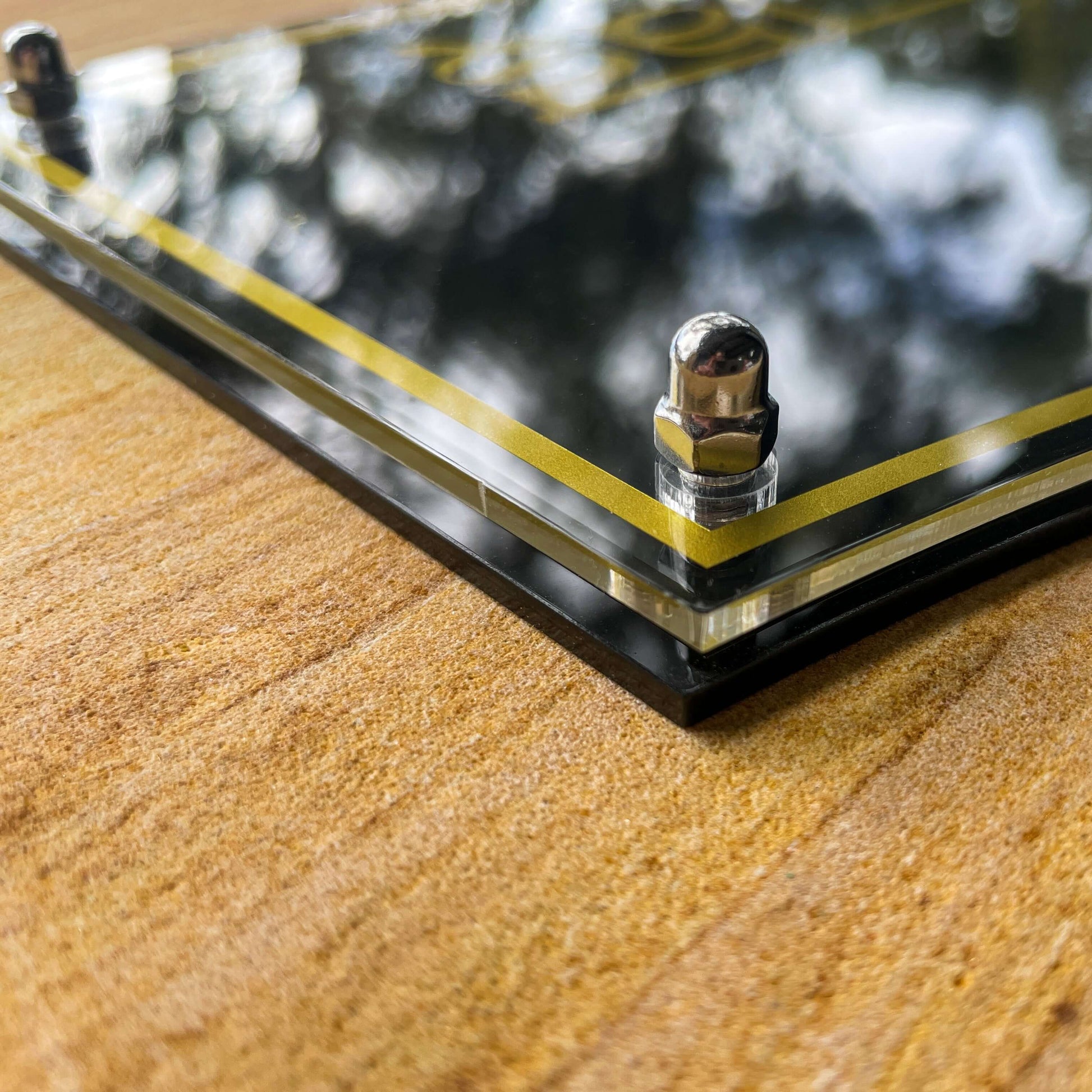 Close-up of Australian made SW2 house number sign with stainless steel fittings on wood surface