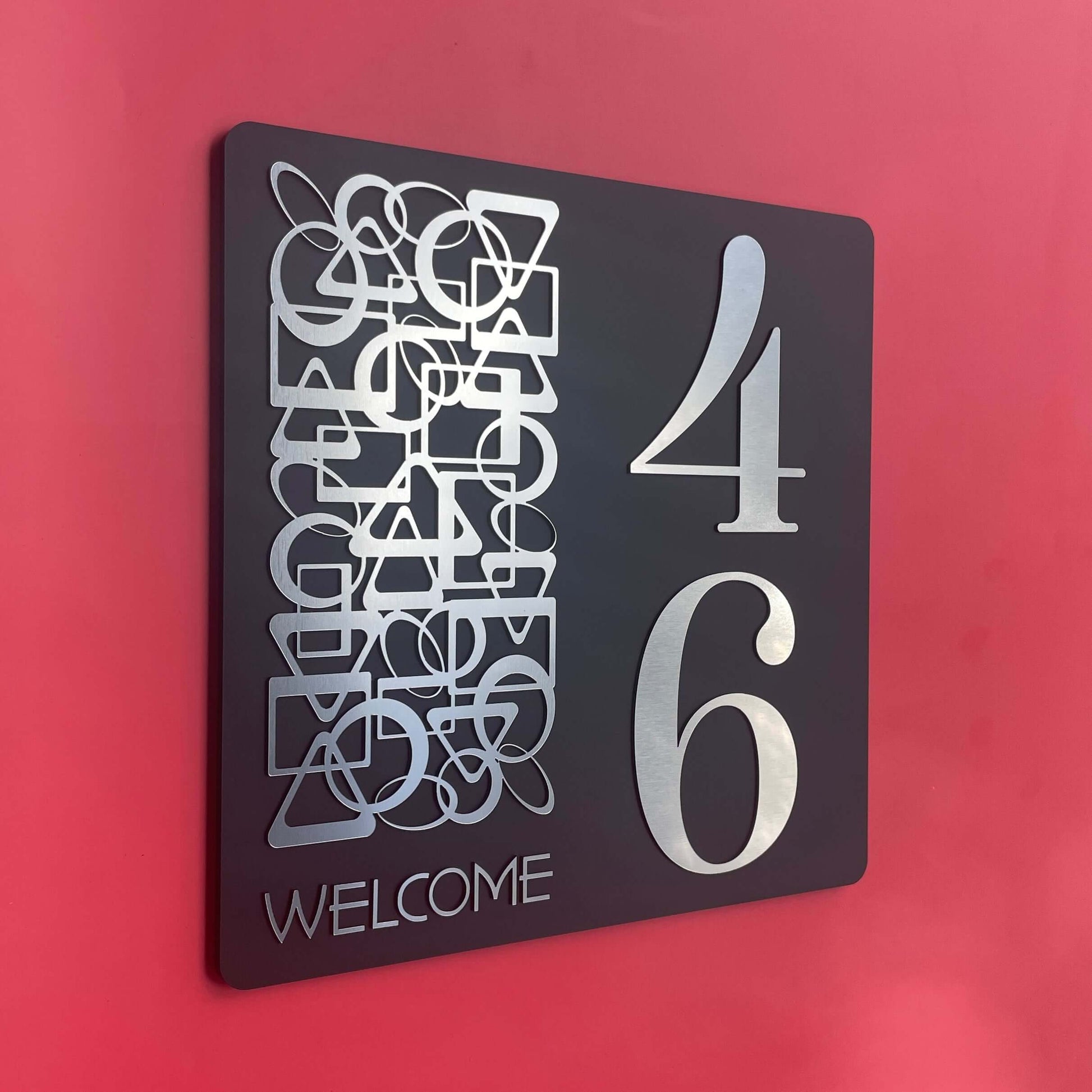 SW2 house number sign with abstract design and large silver numbers on a red wall background.