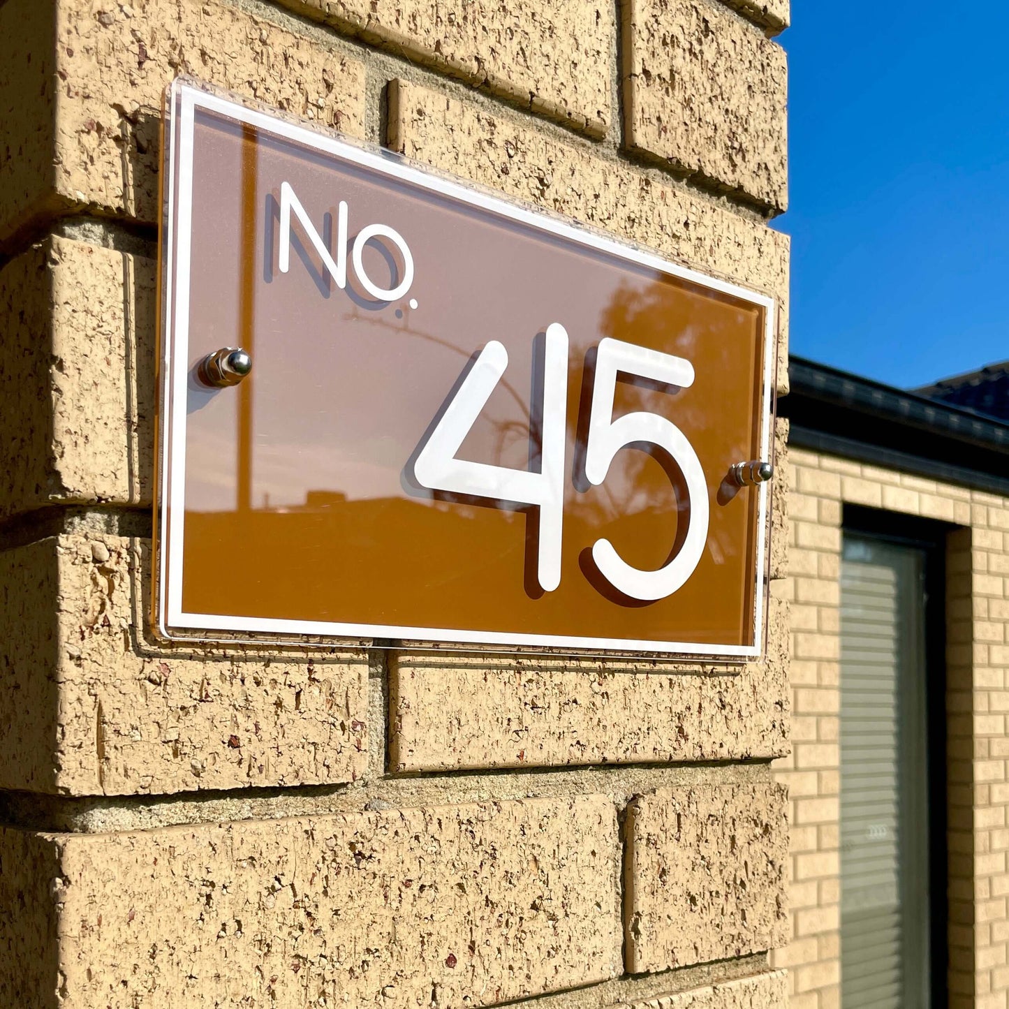 Brown house number sign 'No. 45' mounted on brick wall, featuring modern design. Ideal for 1-3 numbers. SW2 house number sign.